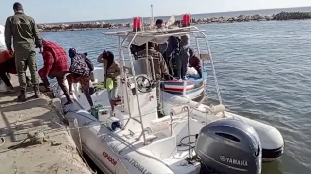 A Tunisian national coast guard helps migrants to get off a rescue boat in Jbeniana, Safx, Tunisia April 23, 2022, in this screen grab taken from a handout video taken 23 April 2022