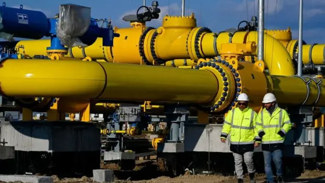 Two men walking in front of a big pipeline