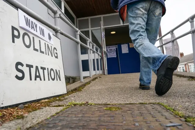 Feet seen walking up a ramp into a polling station