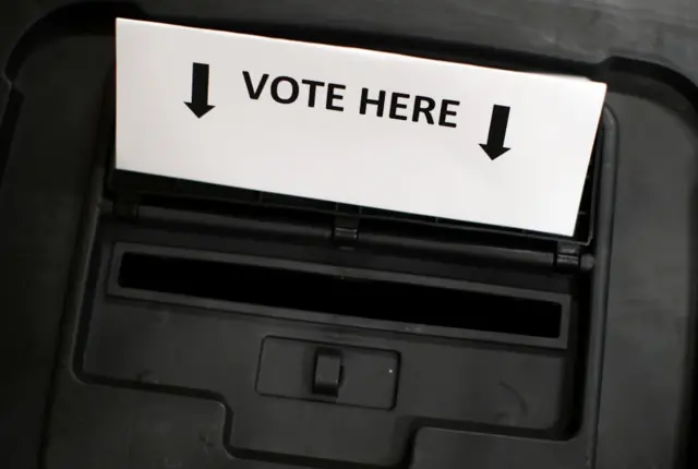 Ballot box labelled with a 'vote here' sign