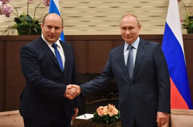 Image shows Putin and Bennett shaking hands