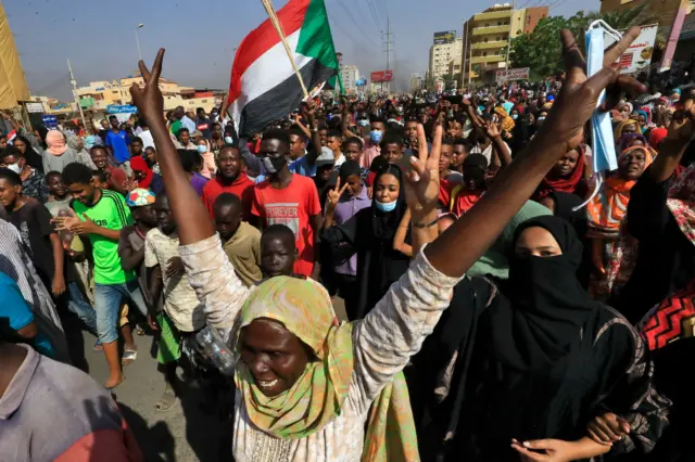 Sudanese protesters lift national flags as they rally on 60th Street in the capital Khartoum last year