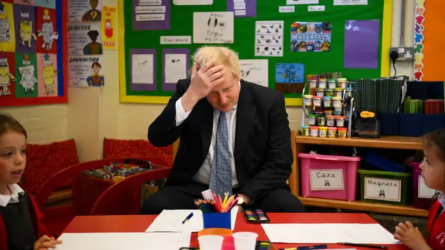 Prime Minister Boris Johnson reacts as he prepares to paint with children during a visit at the Field End Infant school, in South Ruislip, following the local government elections