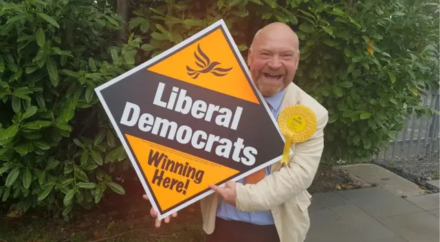 Bill Revans holds up a 'Lib Dems winning here' sign