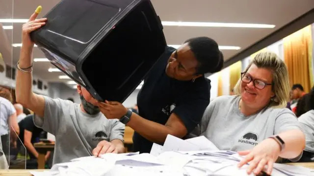 Counter looks for more ballots as they are emptied from a ballot box