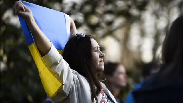 A protester carries a Ukrainian flag during a demonstration against the Russian invasion of Ukraine in front of the Permanent Mission of the Russian Federation to the United Nations in Geneva, Switzerland, 24 March 2022