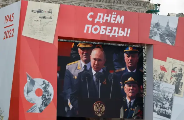 Vladimir Putin seen on a big screen making his speech