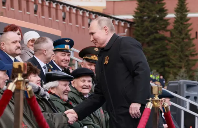 Vladimir Putin greets members of the audience at the Victory Day parade