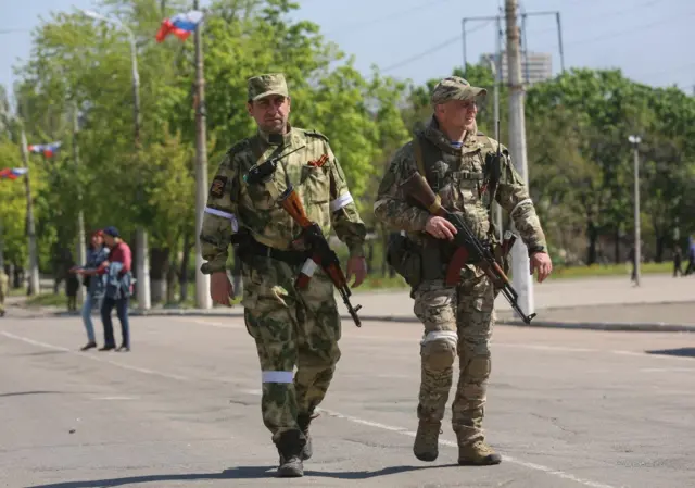 Two militias from the self-declared Donetsk People's Republic walk down a Mariupol street