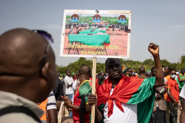 demonstrator holds a placard during a march called by the opposition to protest against the security situation worsening and asking for a response to jihadist attacks, in Ouagadougou, on July 3, 2021.