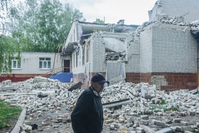 A resident walks past a destroyed building