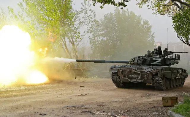 Service members of pro-Russian troops fire from a tank in Mariupol