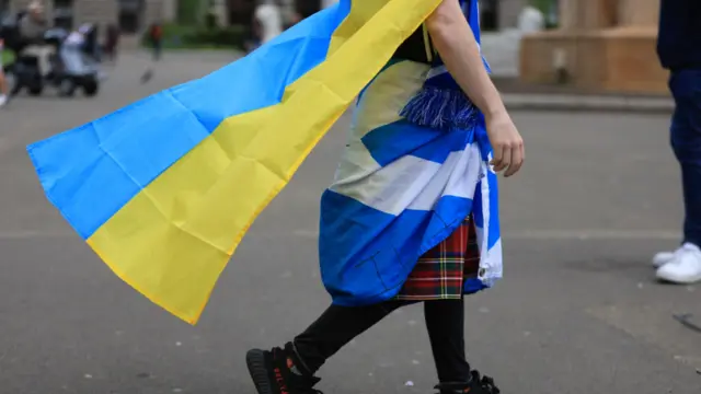 A fan wears a kilt, a Ukraine flag and a Scotland flag before the match