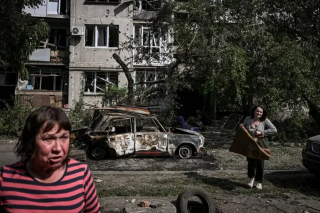 A woman reacts outside a damaged apartment building after a strike in the city of Slovyansk