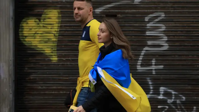 A man and woman wearing Ukrainian colours before the match