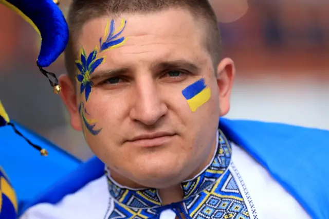 A man wearing Ukrainian colours and with a Ukrainian flag painted on his face