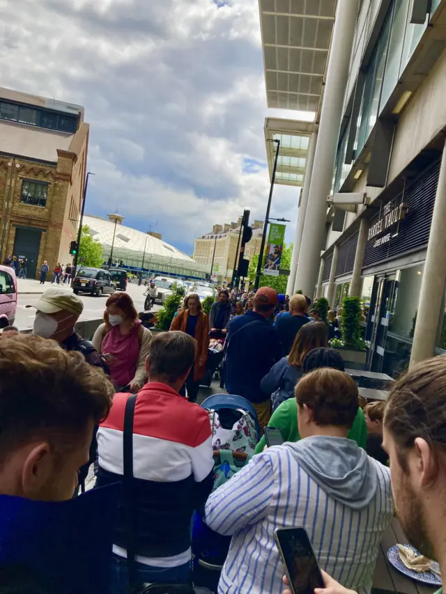 People checking their phones as they queue outside St Pancras station