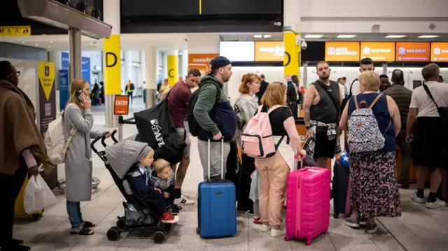 People queuing with their suitcases at an airport