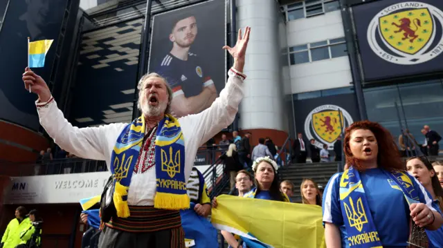 A crowd wearing Ukrainian colours gather outside Scotland's Hampden Park stadium in Glasgow