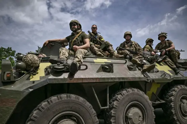 Ukrainian troops sit on an armoured vehicle as they move back from the front line near Slovyansk in the eastern Donbas region