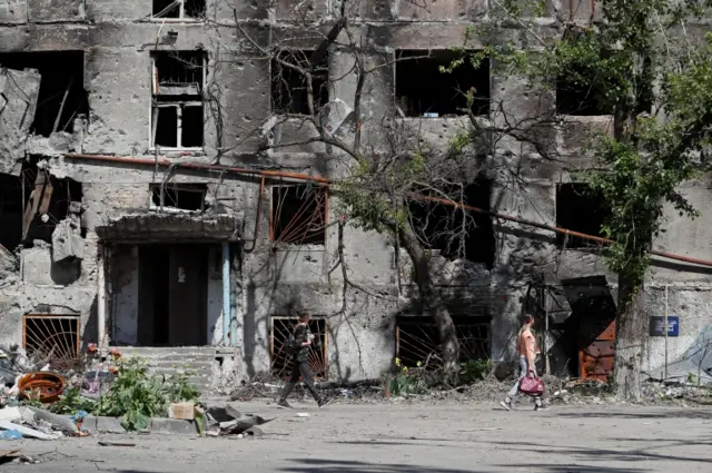 People walk among the ruins of Mariupol