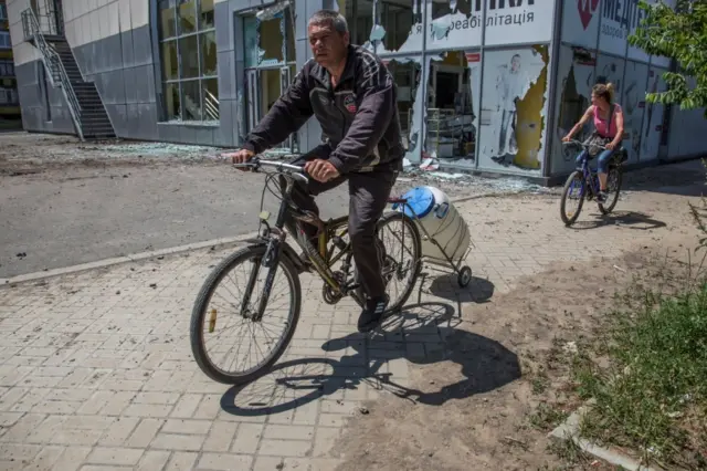 A man rides a bicycle with attached water container