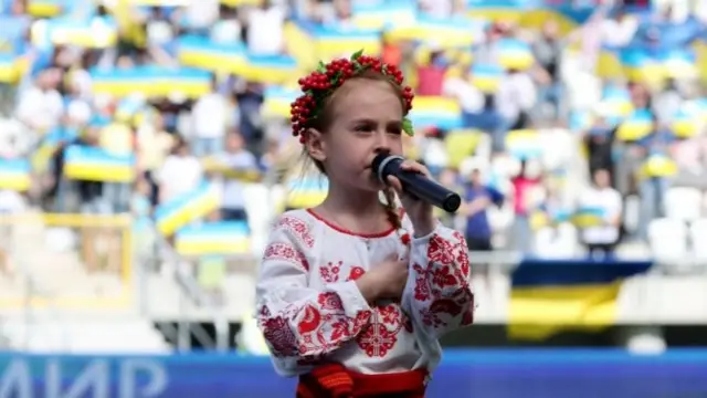 Amelia Anisovich sings the Ukraine national anthem before the match