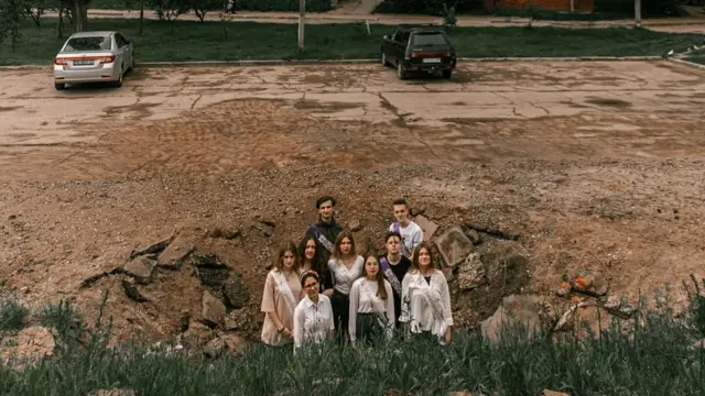 Ukrainian students standing in a crater