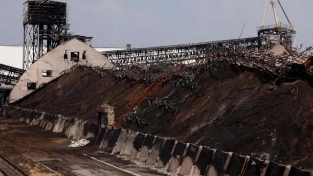 Piles of burnt sunflower seed meal are pictured at a destroyed area of the Nika-Tera grain terminal