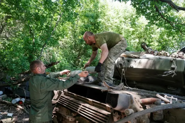 Ukrainian servicemen load shells on to a tank