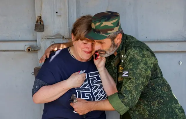 A soldier comforts a woman following recent shelling at the central Maisky market