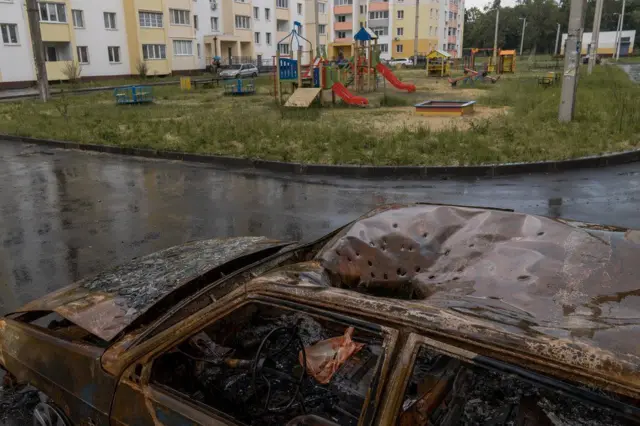 Distinctive marks from a cluster munition in the roof of a car next to a playground in Kharkiv