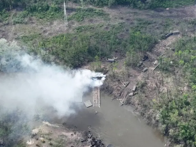 Smoke rises from what appears to be a makeshift bridge across the Siversky Donets river