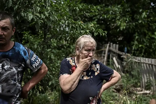 A woman reacts as she stands in the yard of a house where two people were killed during shelling in the city of Lysychansk
