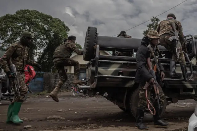 Soldiers ride on a patrol car on National Road 2 at the edge of the area that was attacked by M23 rebels during clashes with the Congolese army in Kibumba,