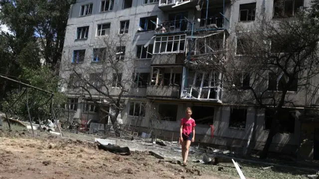 A local resident walks outside her building, partially destroyed as a result of a night airstrike, in the town of Bakhmut, Donetsk Oblast