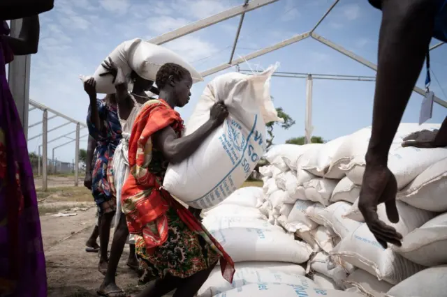 omen from Murle ethnic group carry bags of sorghum during a food distribution by United Nations World Food Programme