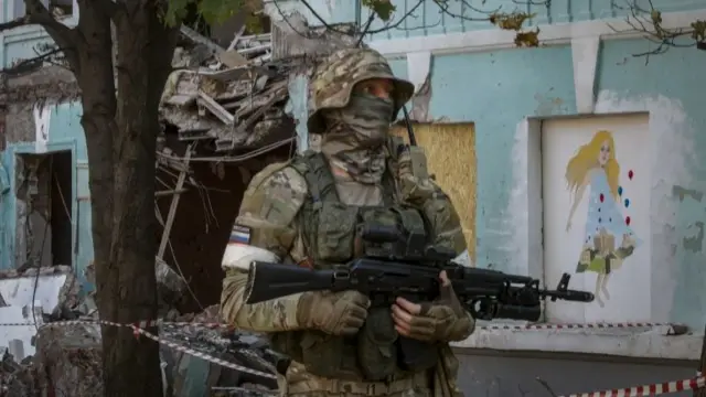 A picture taken during a visit to Mariupol organised by the Russian military shows a Russian serviceman on guard in front of the school No.22 , damaged in a shelling on 30 May in downtown Donetsk, Ukraine