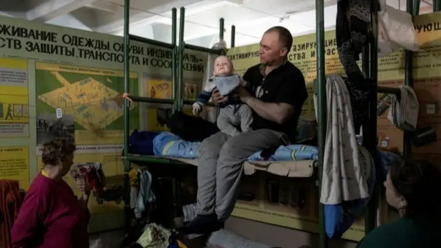 A man holds his baby inside Azot chemical plant"s bomb shelter, where people have been hiding from from shelling since the beginning of the war, in Sievierodonetsk, Luhansk region, Ukraine