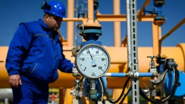 Man stands by gas supply pipe.