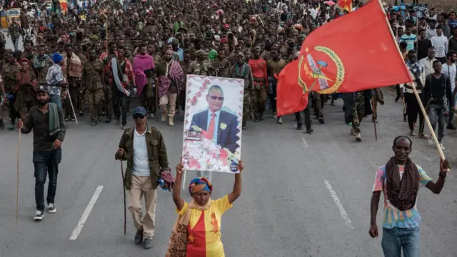 People carry flags for Tigray's pre-war government (L) and the Tigray People's Liberation Front (R) as well as a portrait of its pre-war President Debretsion Gebremichael