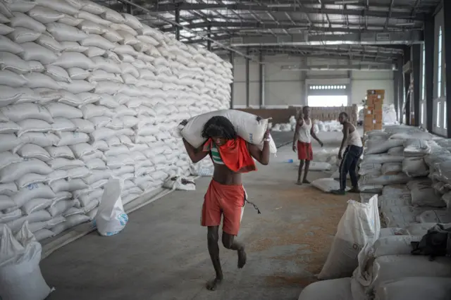 A man carries a bag of wheat to be loaded on an aid truck in a UN storehouse on the outskirts of Semera, Afar region, Ethiopia, on May 15, 2022