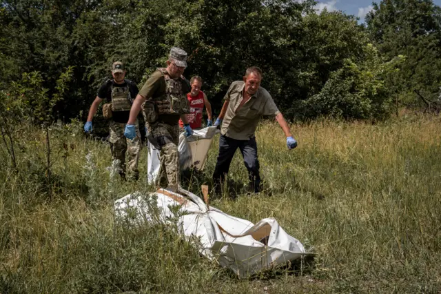 The J9 soldiers and gravediggers carry the bodies out