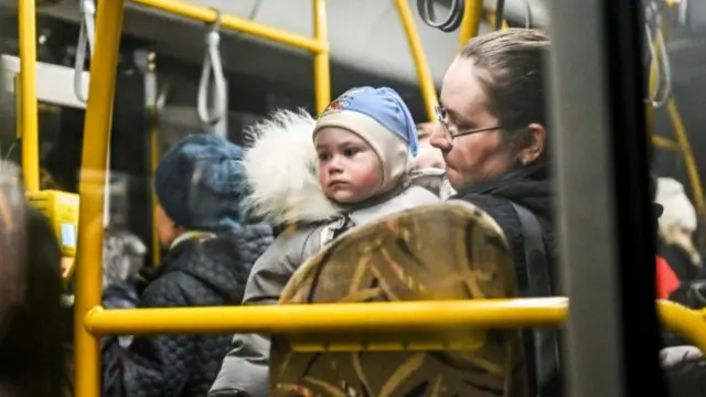 A woman holds a child inside an evacuee bus as people flee from Mariupol and Melitopol amid Russia's attack on Ukraine, at a collecting point in Zaporizhzhia