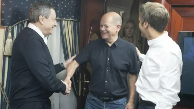 Mario Draghi, German Chancellor Olaf Scholz and French President Emmanuel Macron greeting each other inside a train carriage at an undisclosed location on their way from Poland to Kyiv, Ukraine,