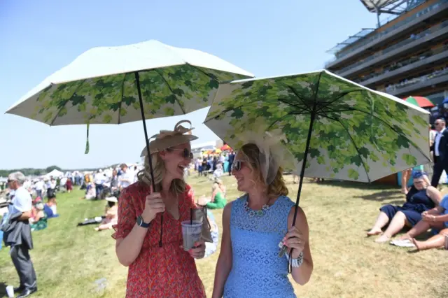 Race-goers shelter under umbrellas on day four of Royal Ascot