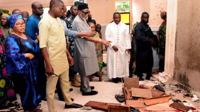 Ondo State governor Rotimi Akeredolu (3rd L) points to blood the stained floor after an attack by gunmen at St. Francis Catholic Church in Owo town, southwest Nigeria on June 5, 2022.