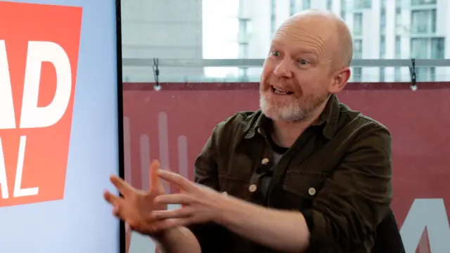 a man gestures with his hands while explaining something in conversation