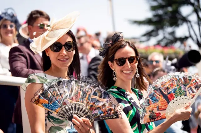 Racegoers fan themselves to stay cool