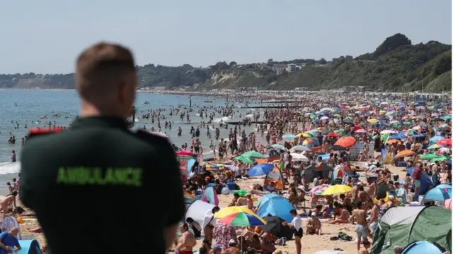 Paramedic stood looking at a full Bournemouth beach